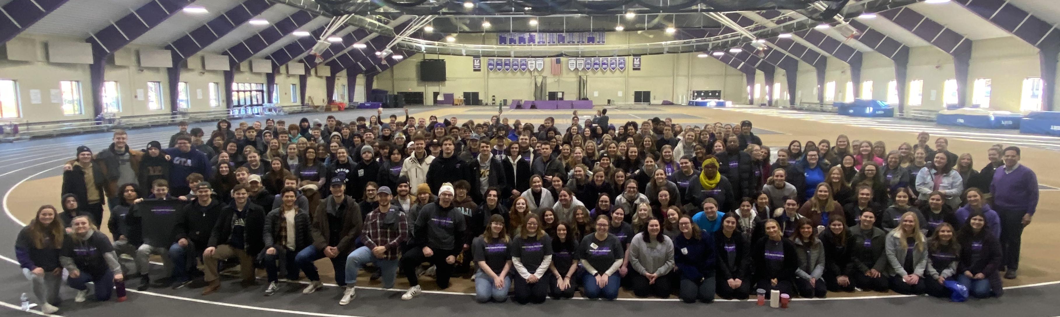 hundreds of volunteers in fieldhouse posed as a group